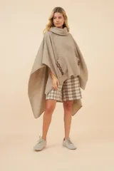 Poncho de lana color marrón con cuello alto, mangas 3/4 y bolsillo lateral con detalle de botones de cuero.