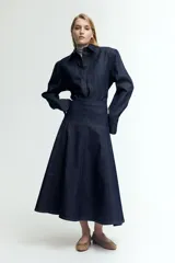 Pollera midi de denim azul oscuro, corte evasé y costuras verticales decorativas.