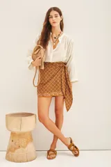 Minifalda estampada color marrón con diseño geométrico, estilo pareo con lazo lateral.