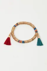 Pulsera elástica con lentejuelas metálicas doradas y plásticas de colores. Incluye borlas de hilo rojas y verde agua.