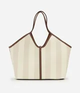 Bolso tipo tote de lona con rayas verticales en tonos beige y marrón claro. Presenta ribetes y asas de cuero sintético marrón oscuro con costuras contrastantes. Tiene un cierre central con tira de ajuste y hebilla metálica dorada.