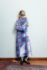 Vestido largo de crepe estampado con diseño geométrico en tonos azules, rojos y blancos. Tiene mangas largas acampanadas y cuello redondo.