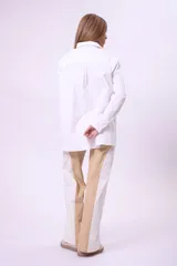 Pantalón de vestir color beige con recortes geométricos en blanco.