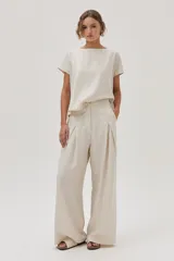 Blusa color crema de lino metalizado, de calce recto, con cuello bote y mangas cortas.