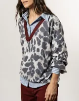 Sweater de punto con cuello en V y estampado animal print en tonos grises y blancos. Tiene ribete marrón en el cuello, puños y bajo elastizados.