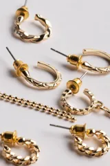 Pack de seis pares de aros dorados con diferentes diseños: aros tipo argolla con textura, aros con dije de estrella, aros con cadena colgante y aros lisos.