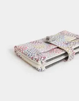 Billetera con formato de fichero, con estampado de corazones multicolores. Tiene doble compartimento con cierre superior y bolsillo frontal con lazo y broche metálico. Cuenta con compartimentos para tarjetas y billetes.
