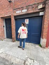 Remera color crema de corte oversize con estampado de flores y frutas en la espalda.