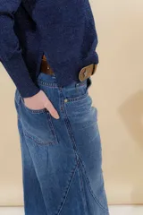 Pantalón de jean color beige, de tiro medio, corte amplio y ruedo acampanado.