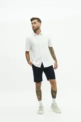 Camisa de manga corta color beige, con textura tipo crepé y cuello camisero.