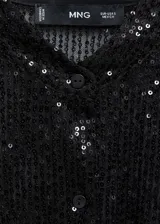 Camisa negra de poliéster con lentejuelas, corte recto, cuello mao y cierre frontal con botones.