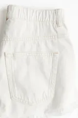 Short de jean blanco de tiro alto, con cinco bolsillos, corte holgado y bajo desflecado.