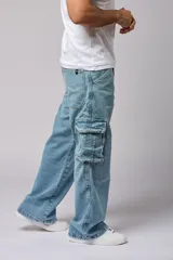 Pantalón jean celeste de corte amplio, estilo cargo, con bolsillos laterales con fuelle y solapa.