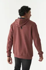 Canguro de felpa color ladrillo con capucha y cordones ajustables. Estampado frontal con la frase "Regret nothing" y logo de la marca Mistral.