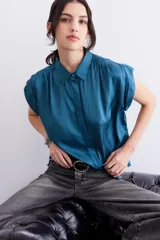 Camisa azul petróleo de viscosa y modal, con cuello camisero, manga corta y frunces en los hombros.