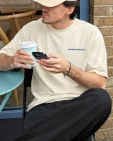 Remera de algodón color beige claro, corte oversize y manga corta. Presenta un estampado en la espalda con el texto "BOHEMIAN DSG®" en azul y debajo "CERTIFIED AUTHENTIC STREETWEAR" en letras más pequeñas.