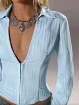 Camisa celeste de mangas largas con cuello clásico y cierre frontal con botones. Diseño entallado con textura vertical.