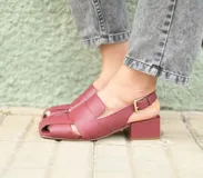 Sandalia de cuero color borgoña, con punta cuadrada y tiras anchas entrecruzadas. Tiene talón abierto con pulsera ajustable y taco ancho forrado de 4 cm.