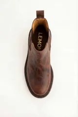 Bota tipo Chelsea de cuero legítimo en color marrón con acabado texturizado. Presenta paneles elásticos laterales al tono, tirador trasero para facilitar el calce y suela de goma gruesa con vira pespunteada.