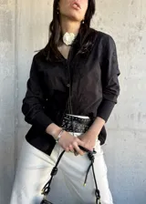 Camisa negra con bordado floral, de manga larga y corte recto.