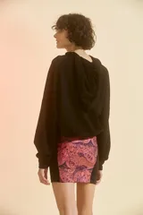 Minifalda de tiro alto con cierre frontal y elástico en la cintura. Presenta recortes laterales en color negro y estampado paisley en tonos rosa y violeta.