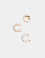 Set de tres cuffs dorados con diferentes diseños: uno con perlas, otro con forma de cadena y otro con un corazón.