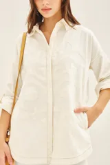 Campera manga larga color marrón con cuello camisero, confeccionada en gabardina con parches bordados en delantero y espalda.