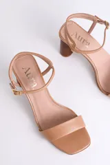 Sandalias de cuero negro con tacón cilíndrico de madera y tira fina con hebilla al tobillo.