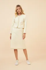 Falda midi color crudo, de corte recto con detalle de galón tejido aplicado en el ruedo.