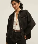 Campera trucker de jeans negro con efecto tintado, cuello clásico, cierre frontal con botones, solapas en el pecho con botones y corte holgado.