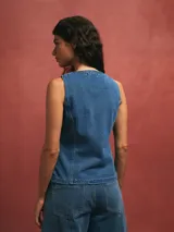 Chaleco de jean azul con botones y bolsillos frontales.