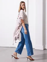 Kimono tejido con estampado abstracto en tonos beige, blanco y negro. Tiene mangas amplias estilo japonés y terminación de ruedo con borlas.