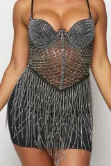 Vestido corto de fiesta de tul elastizado negro con apliques de strass tornasolado y tiras de strass en la falda. Tiene tiras regulables, abdomen semi transparente, falda con forro interno y cierre invisible al costado.