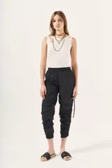 Pantalón jogger negro de nylon con elástico ancho en la cintura, puños elásticos ajustables y lazos laterales para fruncir.
