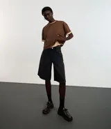 Blusa color beige, cropped y de corte amplio, confeccionada en tejido de media malla, con cuello redondo y mangas cortas.