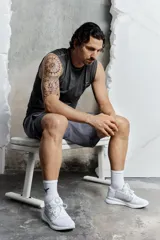 Musculosa deportiva negra con cuello redondo, corte entallado y espalda deportiva. Presenta detalles reflectantes en el pecho y la espalda, y paneles de malla en los laterales.