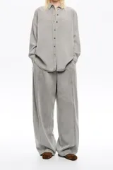 Pantalón de denim gris lavado, tiro bajo, de corte ancho y holgado. Presenta pespuntes a contraste en color marrón claro a lo largo de las costuras.