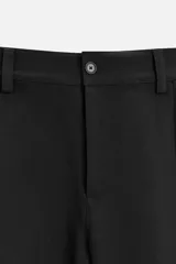 Pantalón negro de corte amplio tipo balloon fit, con cintura con pliegues frontales, bolsillos delanteros y traseros de plastrón. Cierre frontal con cremallera y botón.