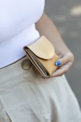 Monedero pequeño de cuero en tonos tostados y plateados, con diseño compacto y cierre de solapa.