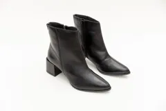 Bota de cuero negra, de caña corta y punta fina, con cierre lateral y taco geométrico de 6 cm.