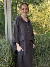 Camisa oversize rosada de lino, con cuello clásico, cierre frontal con botones, dos bolsillos de parche en el pecho y mangas largas con puños abotonados.