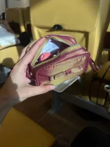 Neceser gris de tela satinada con cierre superior y detalle de moño en el frente.