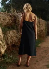 Vestido midi negro de lino y rayón con tiras finas ajustables, escote recto y tajo lateral.