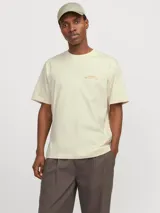 Camiseta color crema de manga corta y cuello redondo con calce holgado. Estampa en la espalda con print de goma de tacto suave.