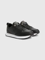 Zapatillas deportivas Tommy Hilfiger negras de cuero sintético, con cordones y suela blanca.