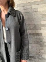 Saco largo gris oscuro tejido en lana merino, con cuello, puños y bolsillos de tejido con diseño de espiga en tono gris claro.