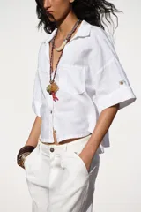 Camisa cropped color rosa de lino, con cuello solapa, escote pico, manga corta y bolsillos delanteros de plastrón.