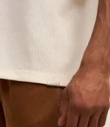 Remera marrón de poliéster y elastano con textura de pana, cuello redondo, manga corta y bordado centralizado de lettering minimalista.