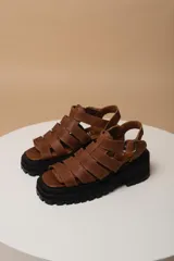 Sandalias marrones de cuero con tiras entrecruzadas y suela track negra.