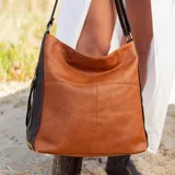 Cartera negra de simil cuero con apertura superior con cierre. Tiene detalle frontal en costura, dos bolsillos internos, un bolsillo divisor en el forro y bolsillos laterales con cierre. Incluye correa larga regulable.